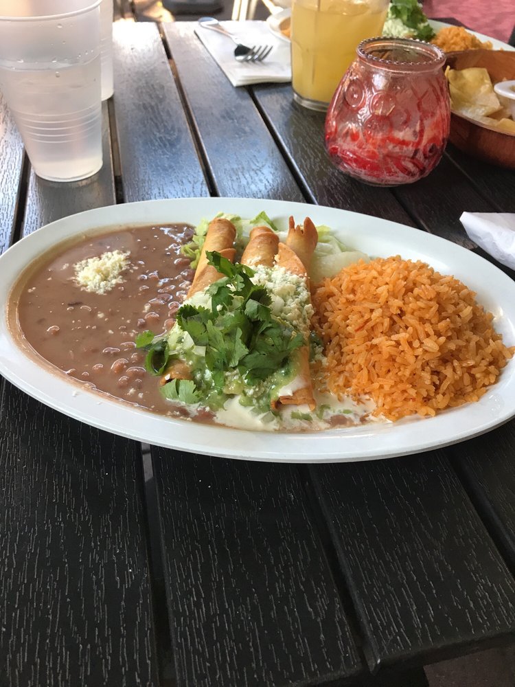 Flautas with rice and beans on a patio table