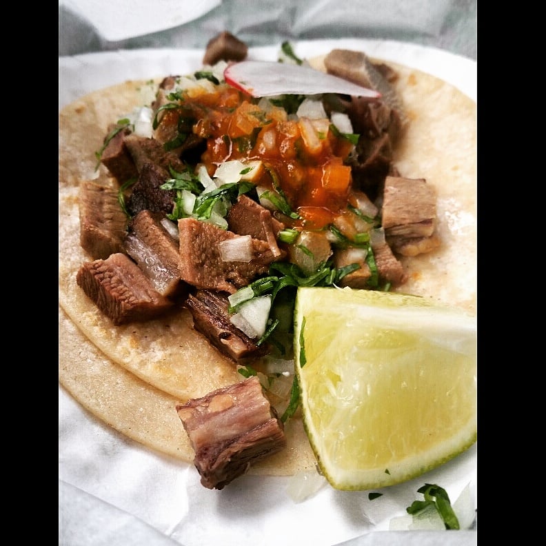 Steak taco with salsa, onion and a lime wedge